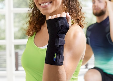 A woman smiling while doing exercise with a wrist support on