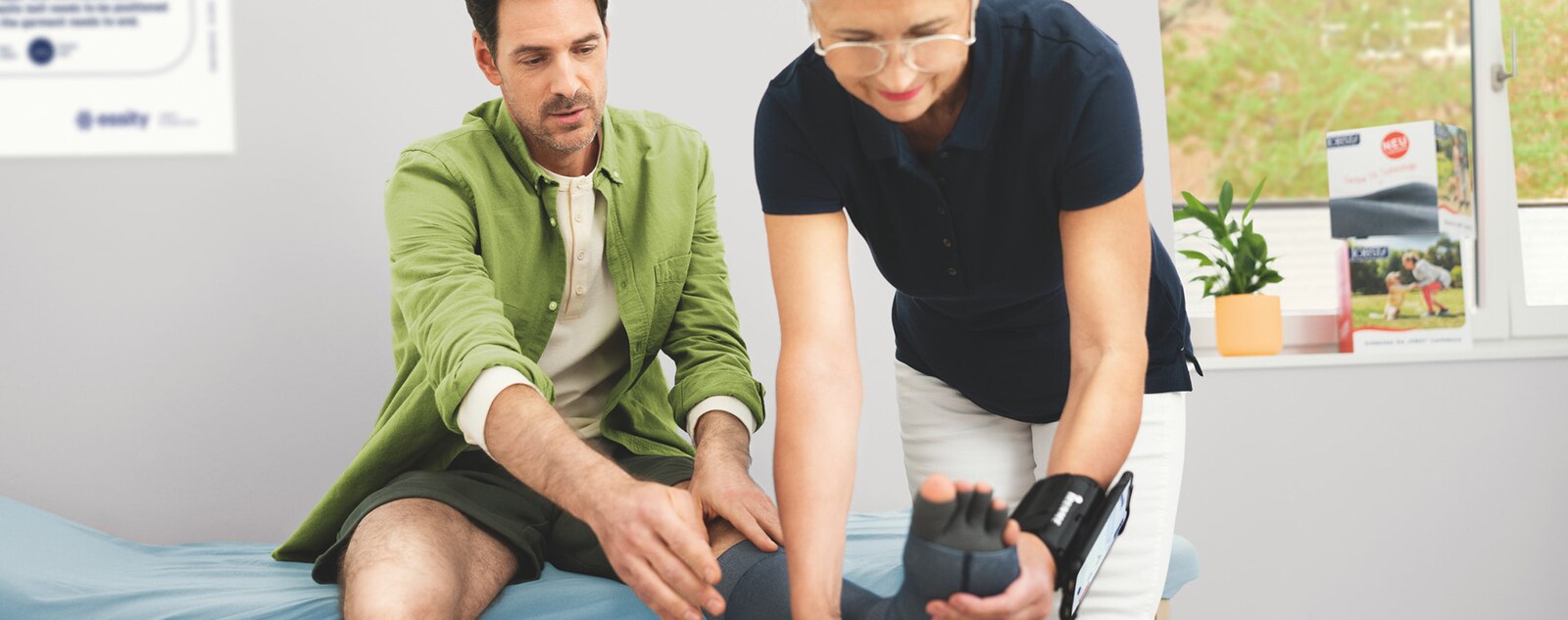 Healthcare professional fitting a compression garment on a patient's foot in a clinical setting.