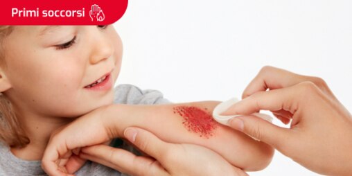 Una persona che pulisce un graffio dal viso di un bambino