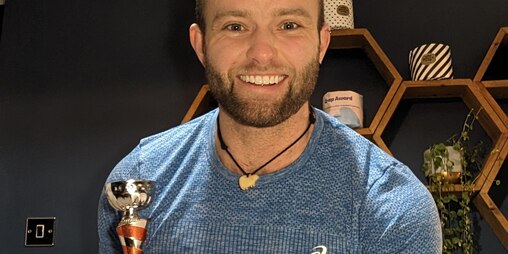 Jamie Gane smiling and holding a trophy in his hands