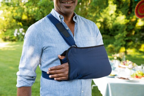 Close up of man attending garden party, wearing an Actimove Professional Line Umerus Comfort Shoulder Immobilizer
