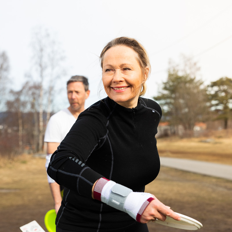 Mann og kvinne spiller frisbeegolf i en park.