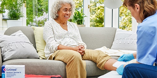 Image of woman having wound dressed by a nurse.