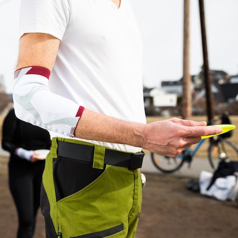 Nærbilde av en arm som har på seg en albuestøtte og holder en frisbee. Nærbilde av en arm som har på seg en albuestøtte og holder en frisbee.