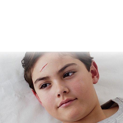 Das Fachpersonal verschließt die Wunde auf der Stirn eines Jungen ohne sie nähen zu müssen.