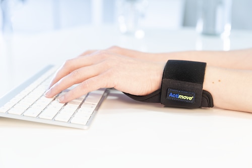 Close-up of hands typing on keyboard, left hand wearing an Actimove Everyday Supports Wrist Stabilizer Carpal
