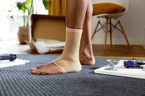 Close-up of man wearing a beige Actimove Arthritis Care Ankle Support