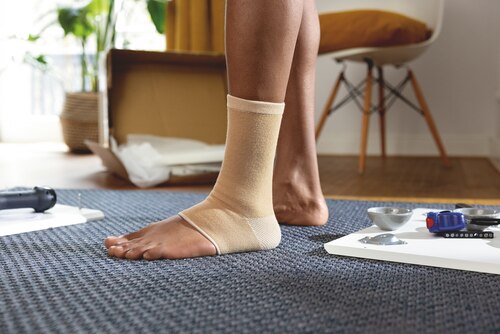 Close-up of man wearing a beige Actimove Arthritis Care Ankle Support