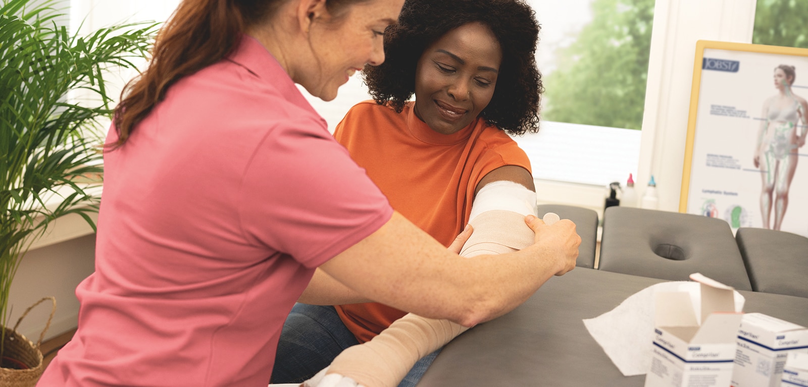 Vårdpersonal lägger på ett kompressionsbandage på en kvinnas arm.