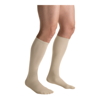 Close-up side view of a person wearing a pair of JOBST Travel compression socks in beige.