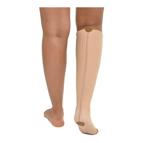 Close-up rear view of a person wearing beige-colored JOBST Relax open-toe, knee-high compression sock on one leg.