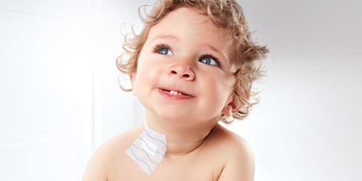 Un bambino contento indossa una medicazione alla base del collo. 