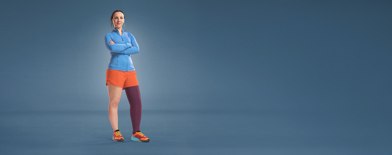 JOBST ambassador Angharad is standing on a blue background, dressed in athletic wear, with a purple compression garment on her leg.