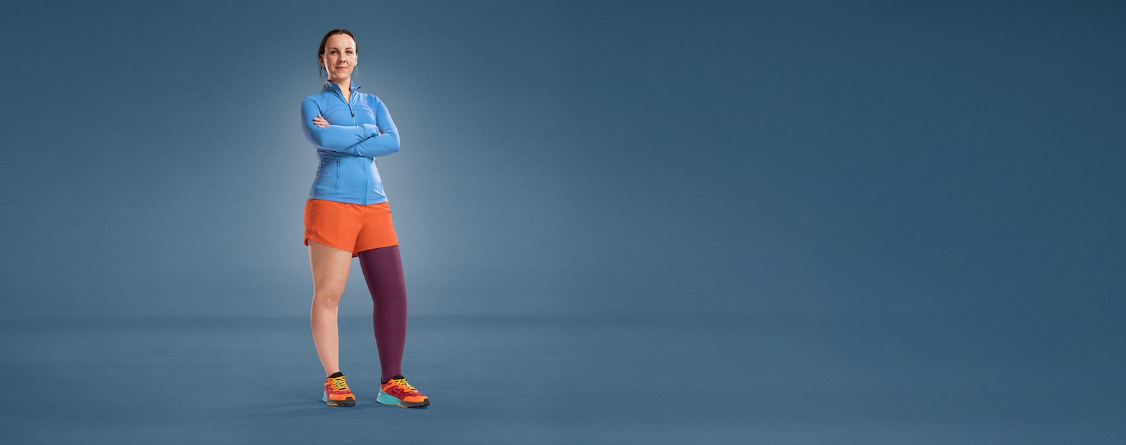 JOBST ambassador Angharad is standing on a blue background, dressed in athletic wear, with a purple compression garment on her leg.