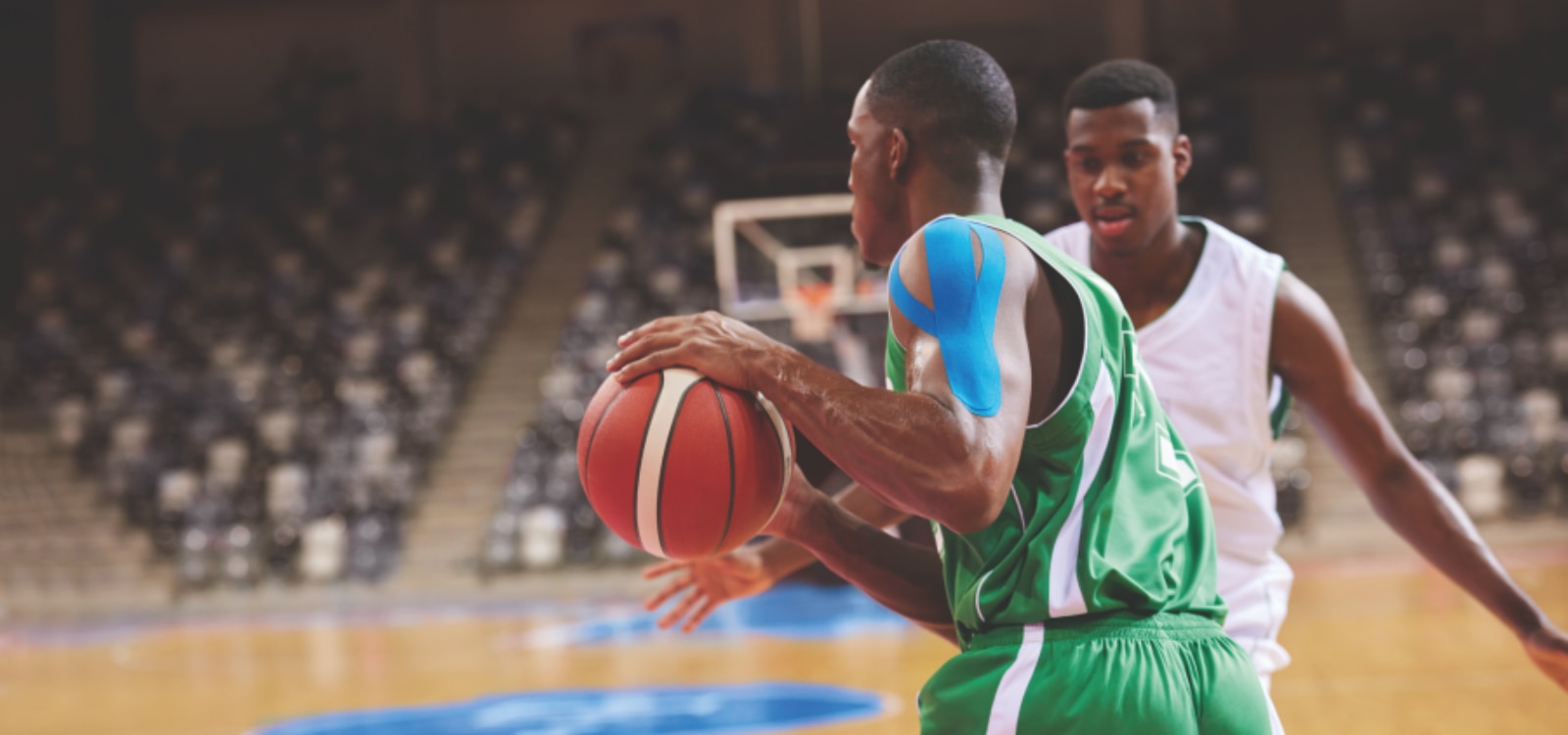 Giocatore di basket professionista che disputa una partita con il taping neuromuscolare Leukotape K sulla spalla.