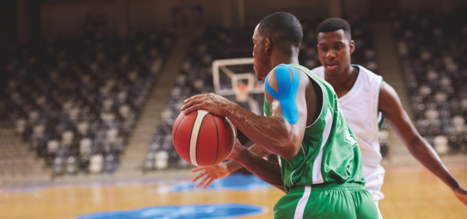 Jugador de baloncesto profesional disputando un partido con vendaje neuromuscular Leukotape K en el hombro.