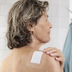 Pansement Leukomed T plus skin sensitive de Leukoplast sur le dos d’une femme âgée après la douche