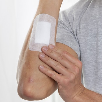 Inspection of Leukomed absorbent dressing by Leukoplast on arm