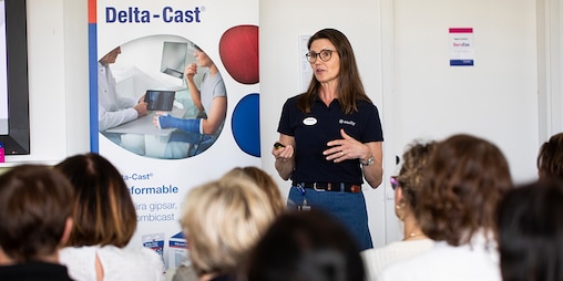 Female trainer is speaking to an audience within a Delta-Cast medical training setting.