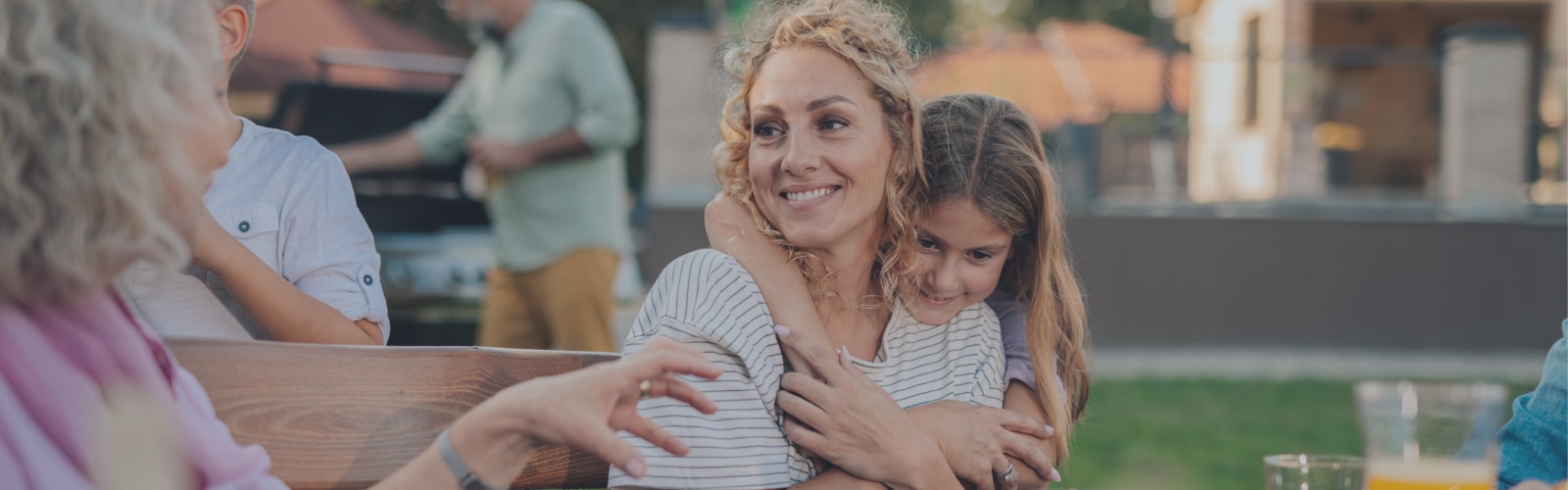 Famiglia numerosa che si gode una grigliata all’aperto in primavera, rilassata e felice, serena grazie alla protezione adeguata in casa contro piccoli incidenti.