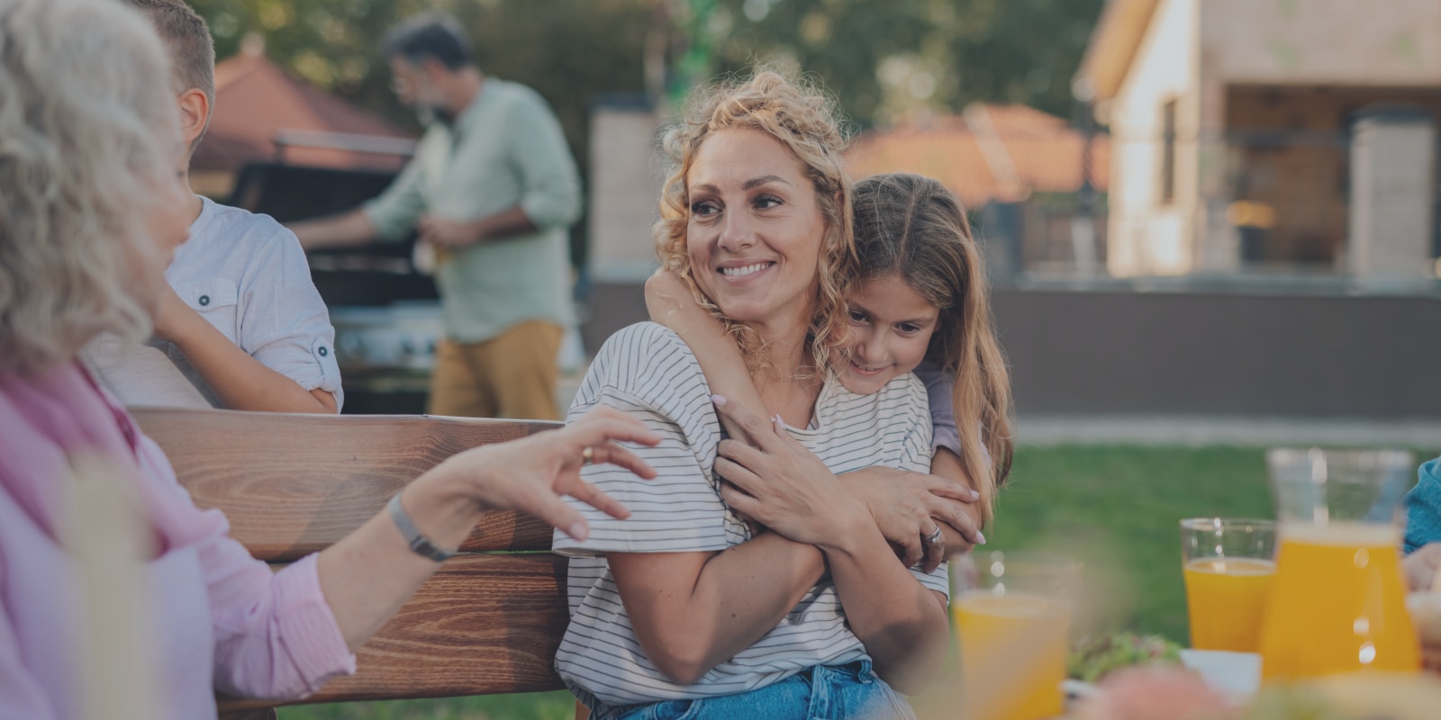 Famiglia numerosa che si gode una grigliata all’aperto in primavera, rilassata e felice, serena grazie alla protezione adeguata in casa contro piccoli incidenti.