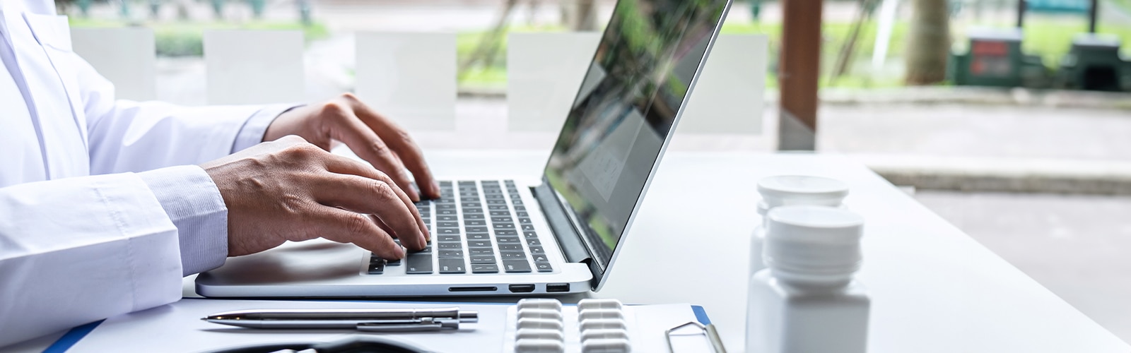 Hände von einem Arzt tippen auf Laptop-Tastatur