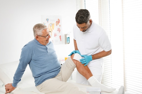 Healthcare professional applying Leukoplast Compress Absorbent Soft dressing to patient’s knee