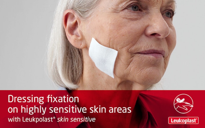 Here we see how to apply and reposition a wound dressing on highly sensitive skin areas, using medical tape: an HCP secures a wound pad on an elderly woman's cheek with fragile skin with the help of Leukoplast skin sensitive.
