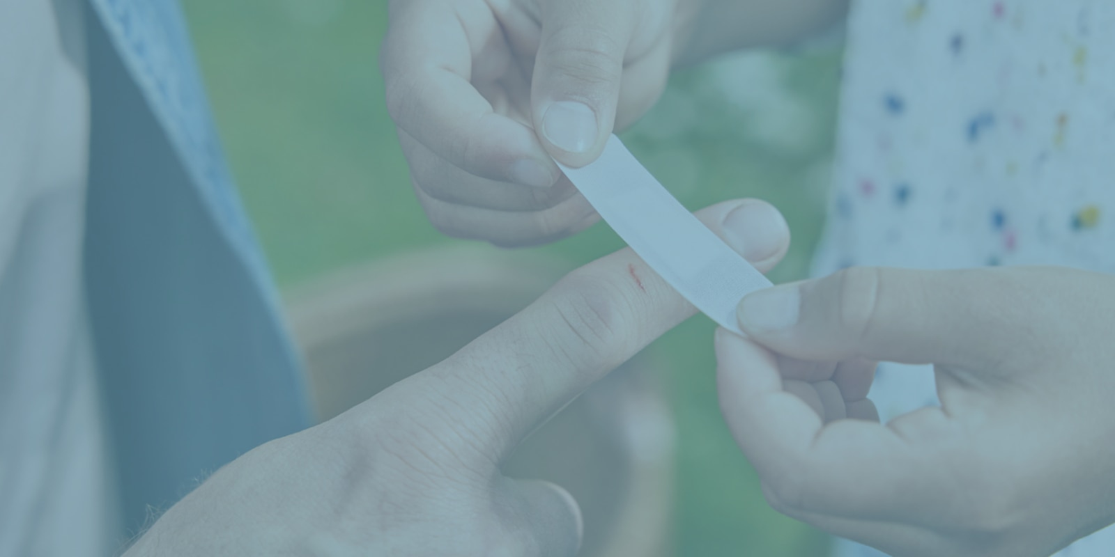 Imagem de uma pessoa a colocar um penso à prova de água no dedo de outra pessoa. 