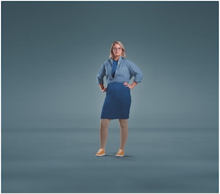 A woman wearing glasses standing against a plain blue background with both hands on her hips, dressed in a blue shirt, blue skirt, orange shoes, and JOBST Relief compression stockings.
