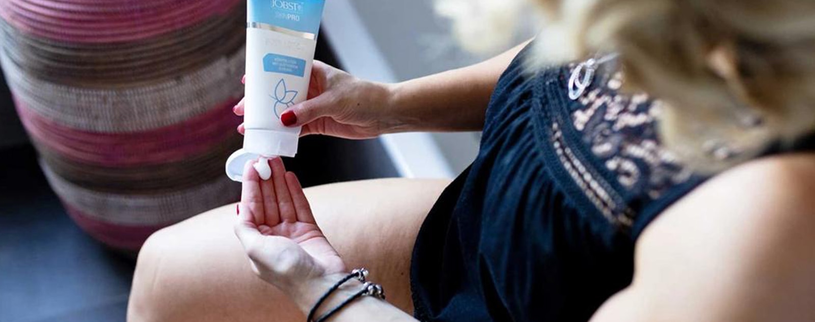 Person squeezing lotion from a tube onto their hand.