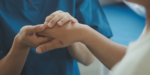Enfermera sujetando una mano de un paciente