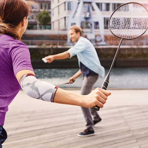 Mann kaster en fjærball mot en kvinne som har på seg en albuestøtte Mann kaster en fjærball mot en kvinne som har på seg en albuestøtte