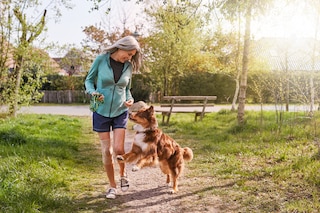Woman outdoors playing with her dog, wearing the Actimove Everyday Supports Knee Support with Closed Patella with 2 Stays
