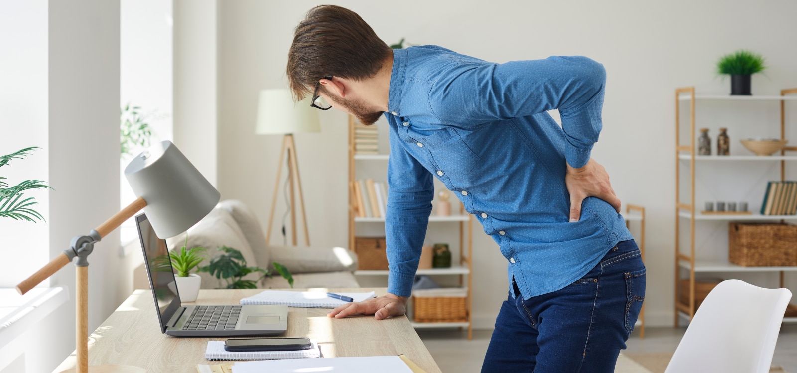 Hombre no cuida la ergonomía en el trabajo y presenta dificultades posturales que le producen lumbalgia.