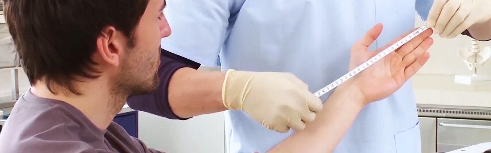 Female doctor and little girl sitting on a daybed in clinic setting, looking and smiling at each other.