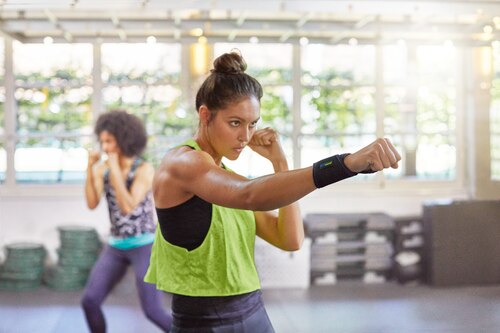 Woman wearing Actimove Sports Edition adjustable wrist support while practicing boxing at the gym
