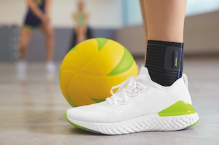 Närbild på kvinna som spelar volleyboll och bär Actimove Sports Edition fotledsstöd med elastiskt band
