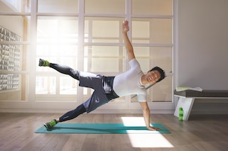 Men at gym performing side plank exercise, wearing an Actimove Sports Edition Back Support with 4 Stays
