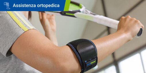 Primo piano di una persona con una gomitiera che solleva in aria una racchetta 