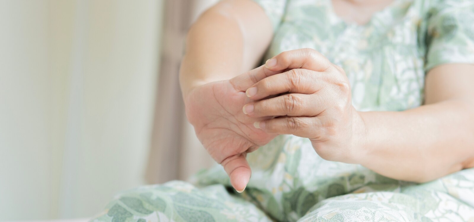 Mujer estirando las articulaciones de las manos debido a los síntomas de la artritis reumatoide.