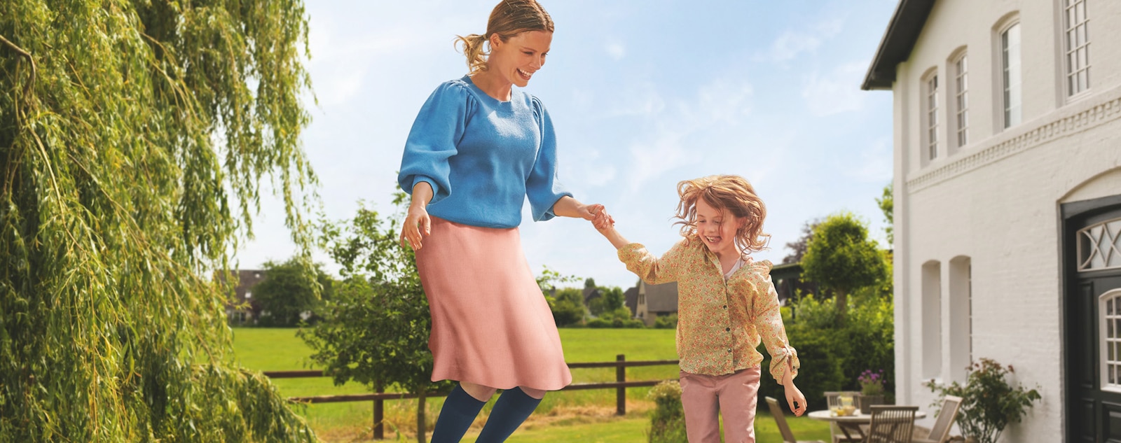 A woman wearing JOBST SoftFit compression stockings jumps on a trampoline with a child.