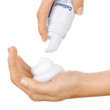 We zien in close-up hoe de ene hand de spray gebruikt en een beetje Cutimed ACUTE Crèmemousse in de palm van de andere hand doet.