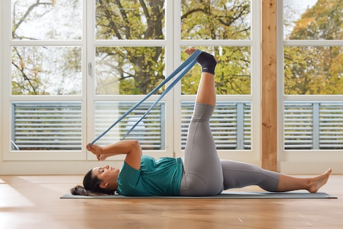 Woman stretching leg while on the mat at gym, wearing Actimove Sports Edition Plus Size Ankle Support
