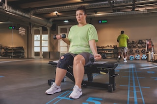 Kvinna på gym som lyfter vikter och bär Actimove Sports Edition justerbart knästöd i plusstorlek
