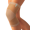 Beige knitted Actimove Arthritis Care Knee Support with heat reflecting technology on slightly bent knee 
