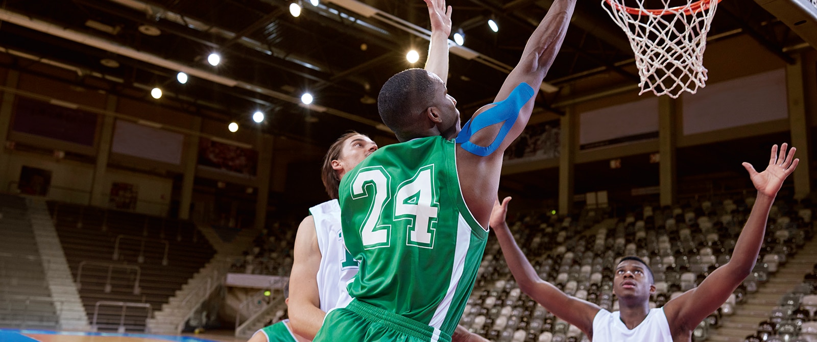 Basketball player using blue kinesiology tape on shoulder during a game.