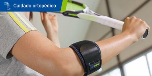 Primer plano de una persona que lleva una codera levantando la raqueta en el aire 