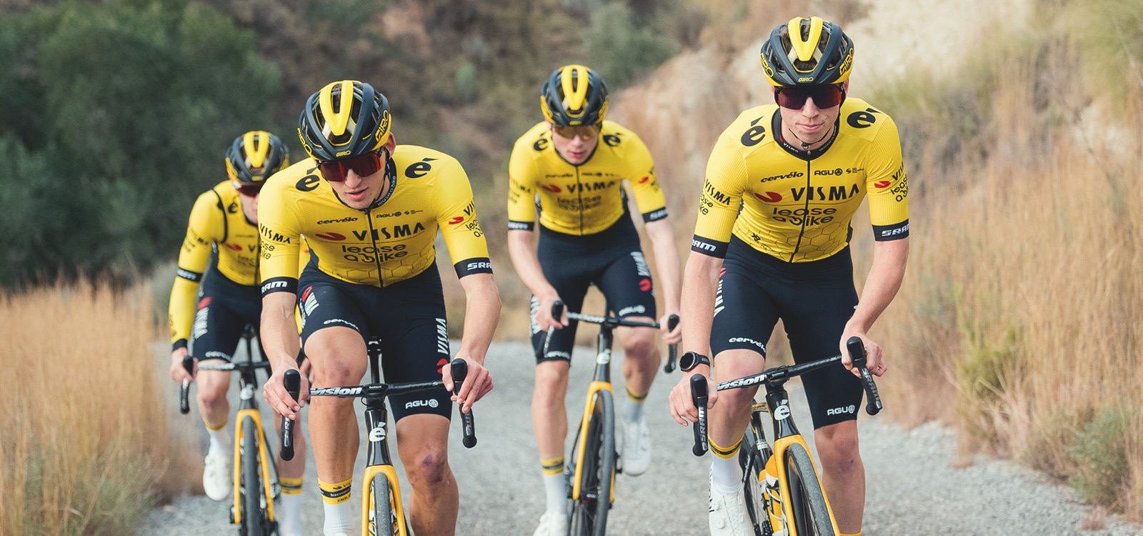 Four cyclists from Team Visma Lease a Bike powering uphill.