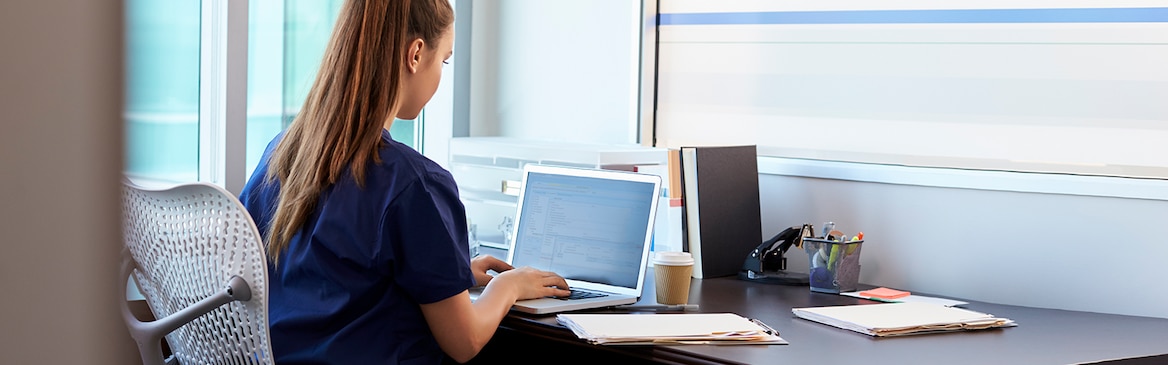 Das Bild zeigt eine junge Frau die an einem Computer arbeitet.